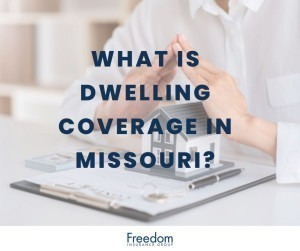 A model of a home on top of paperwork with a man holding his hands to protect the structure.